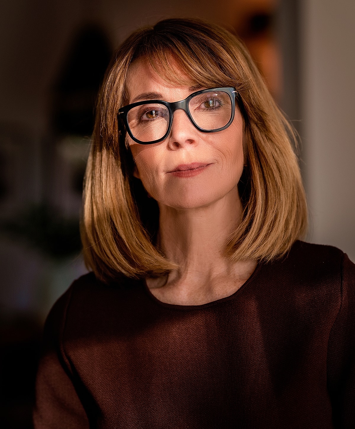 Melbourne deep plane facelift model with glasses in soft, warm lighting.
