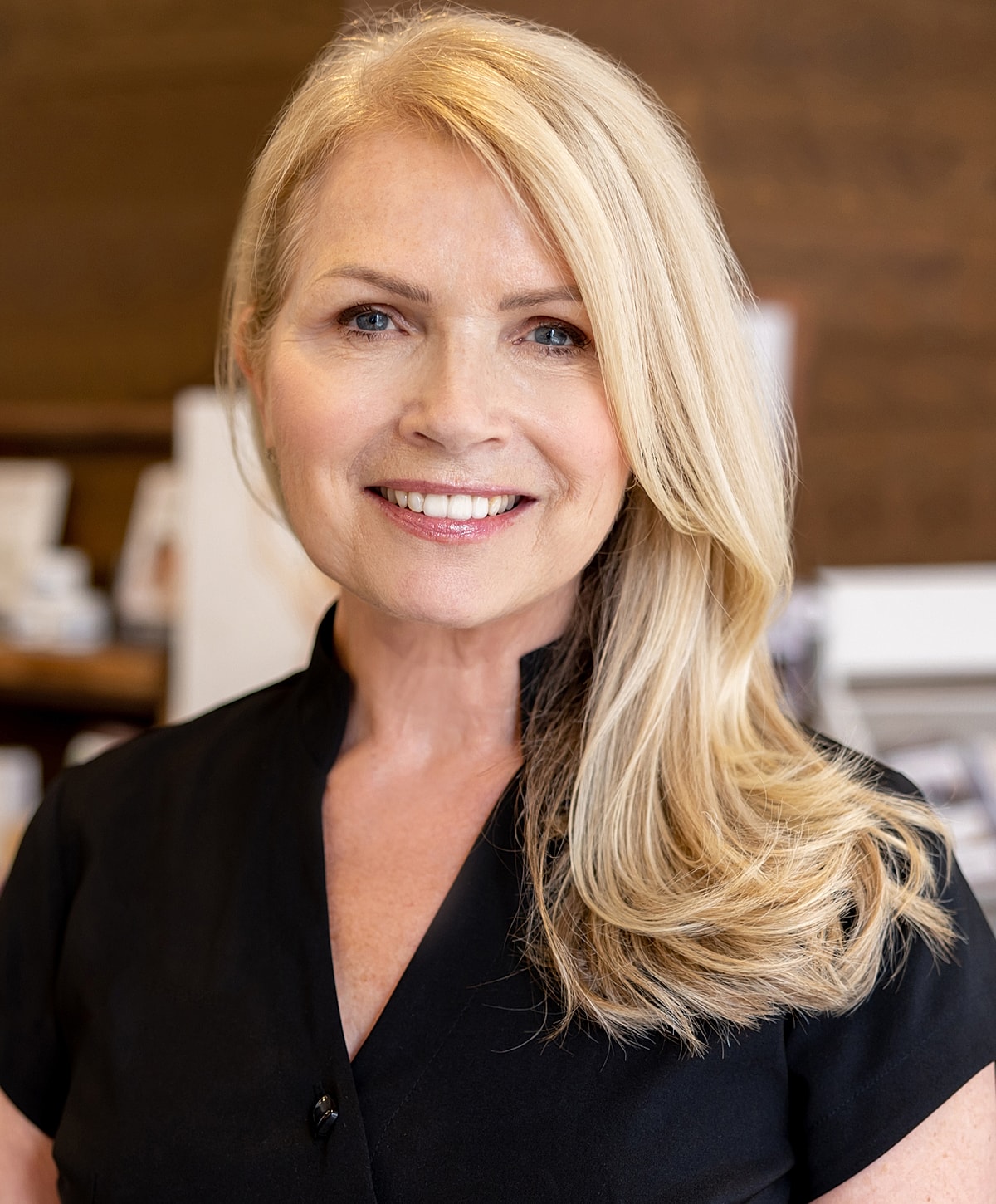 Smiling Melbourne facelift model with long blonde hair, black attire.