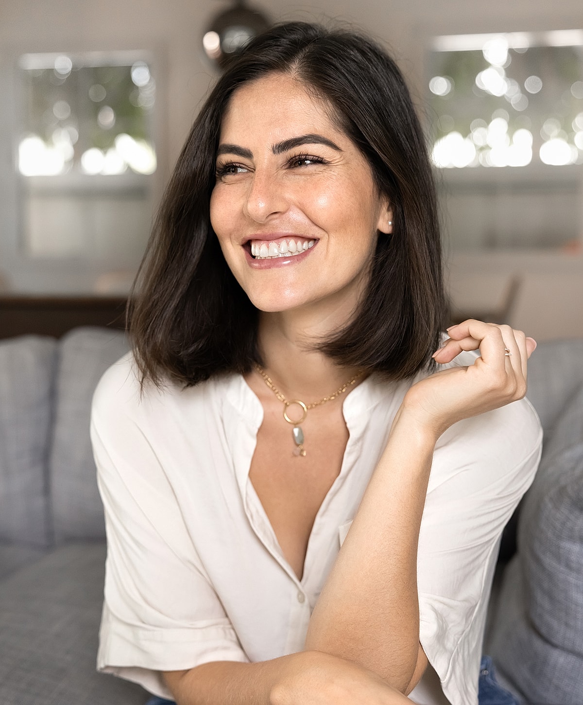 Smiling Melbourne neck lift model wearing a necklace indoors.