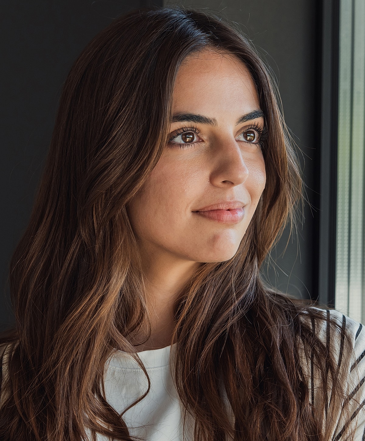 Melbourne lip filler model with long brown hair, thoughtful expression.