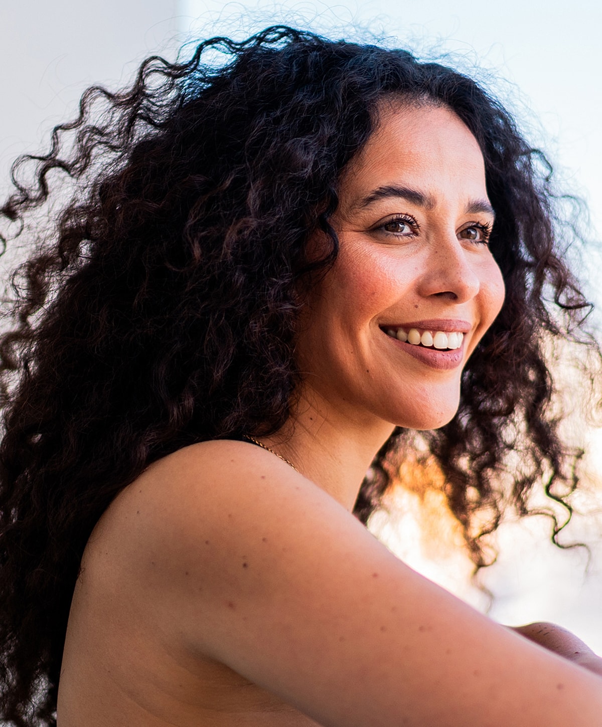 Smiling Melbourne Botox model with curly hair outdoors.
