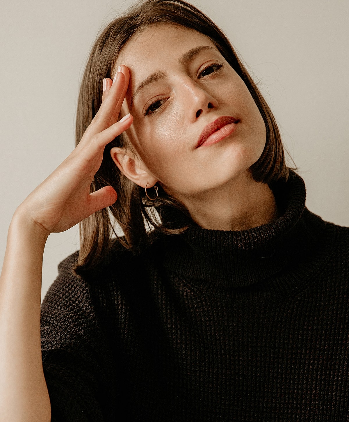 Melbourne microneedling model with hand on forehead, wearing black sweater.