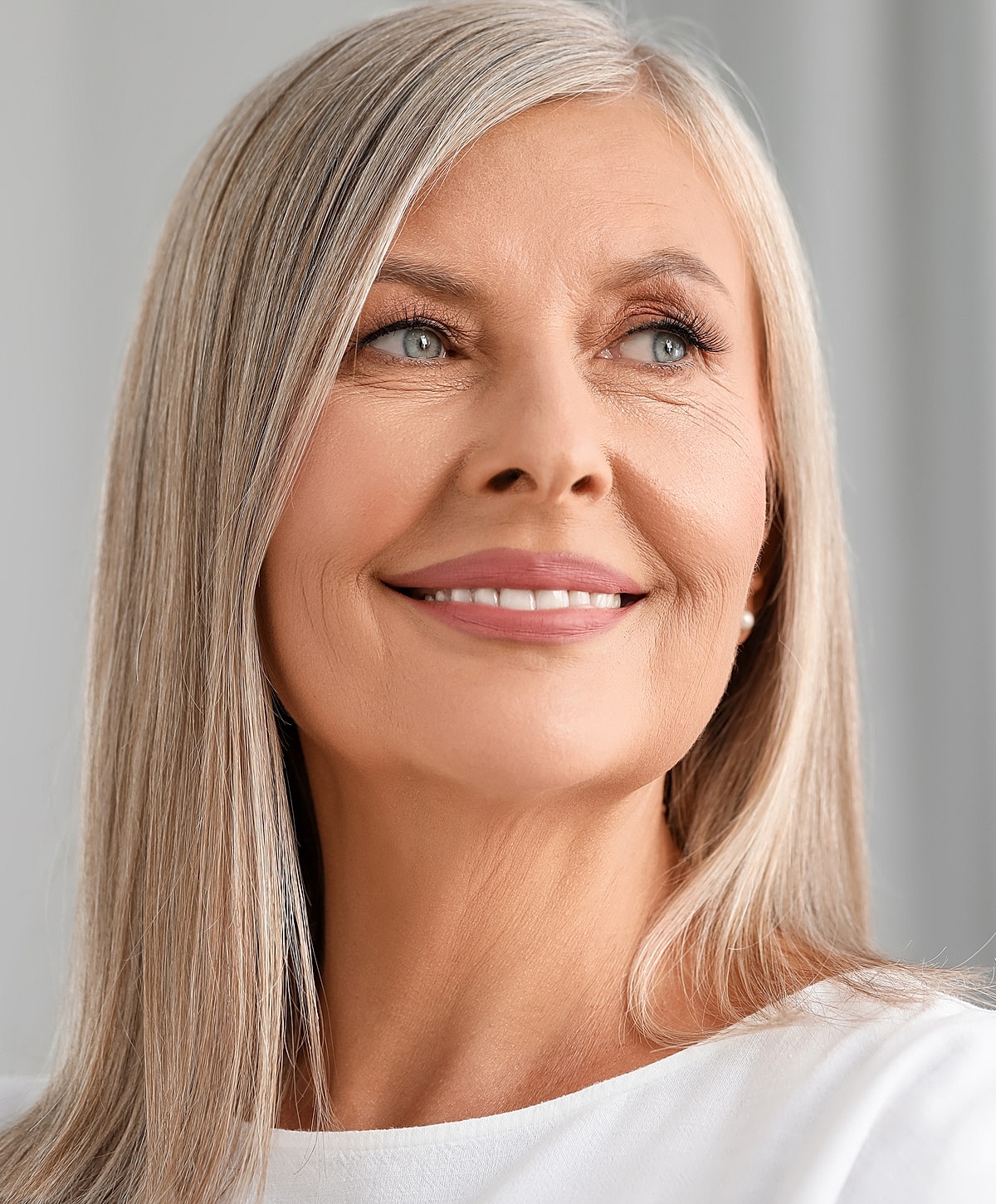 Smiling older Melbourne medical-grade skincare model with long, silver hair.