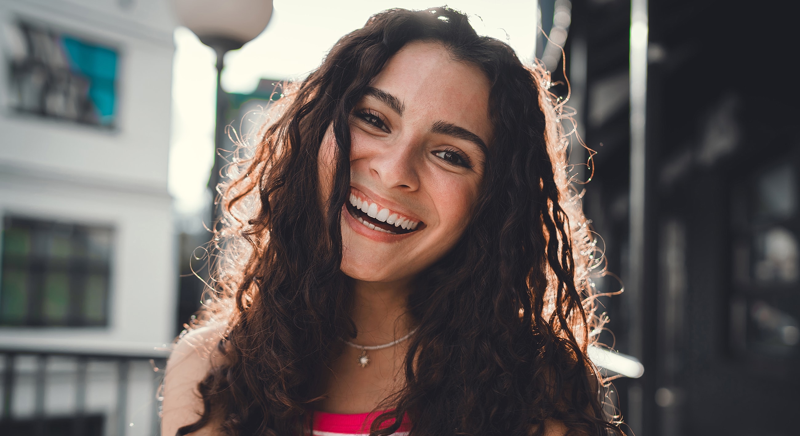 Smiling Melbourne PRP model with curly hair in sunlight.