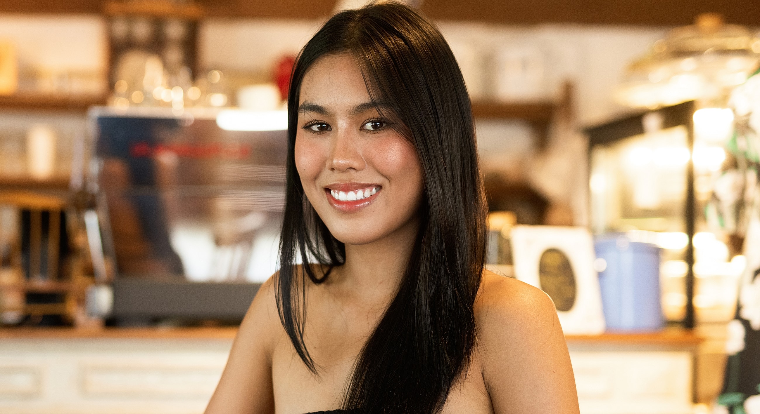 Smiling Melbourne facial balancing model in a cafe setting.