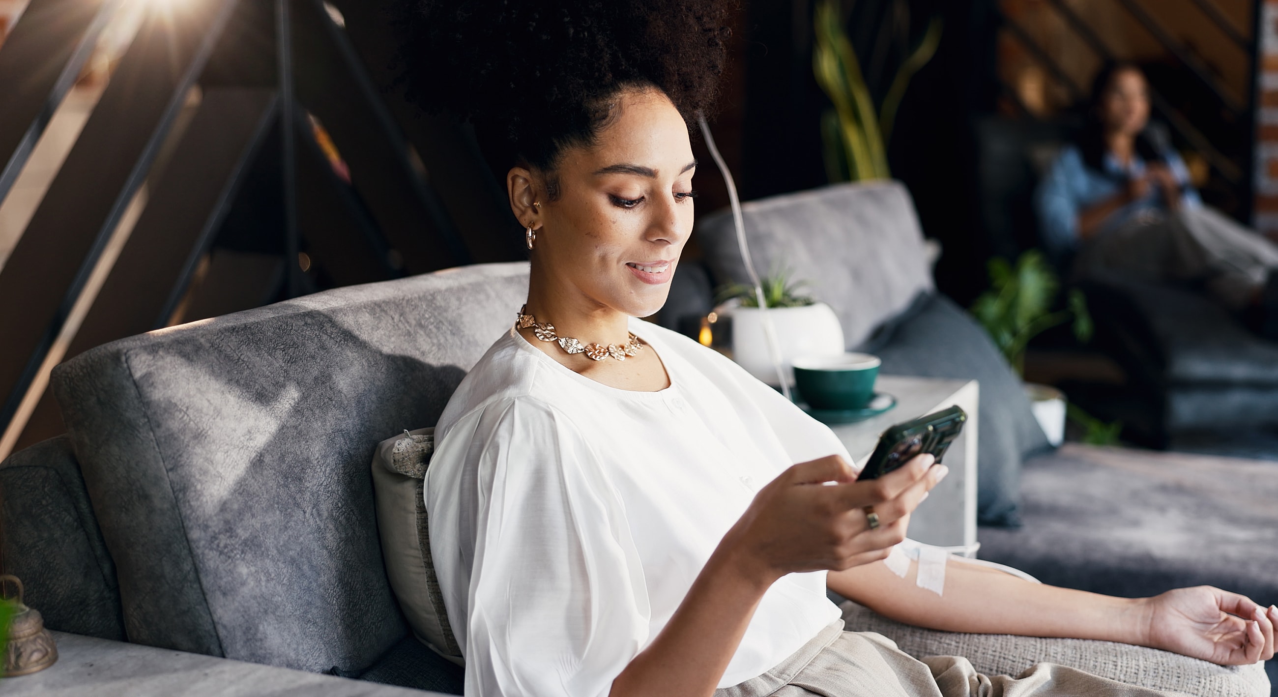 Melbourne IV Therapy model using phone while sitting on couch.