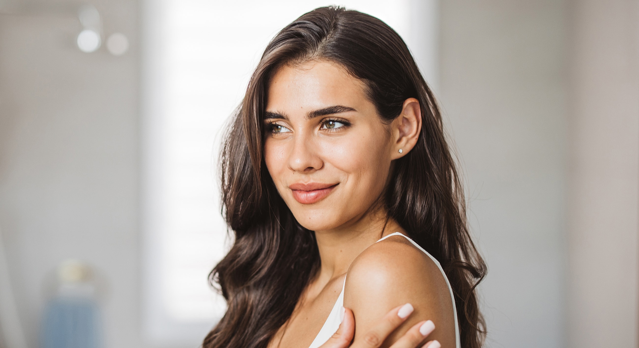Smiling Melbourne CO2 Laser Resurfacing model with long, wavy hair indoors.